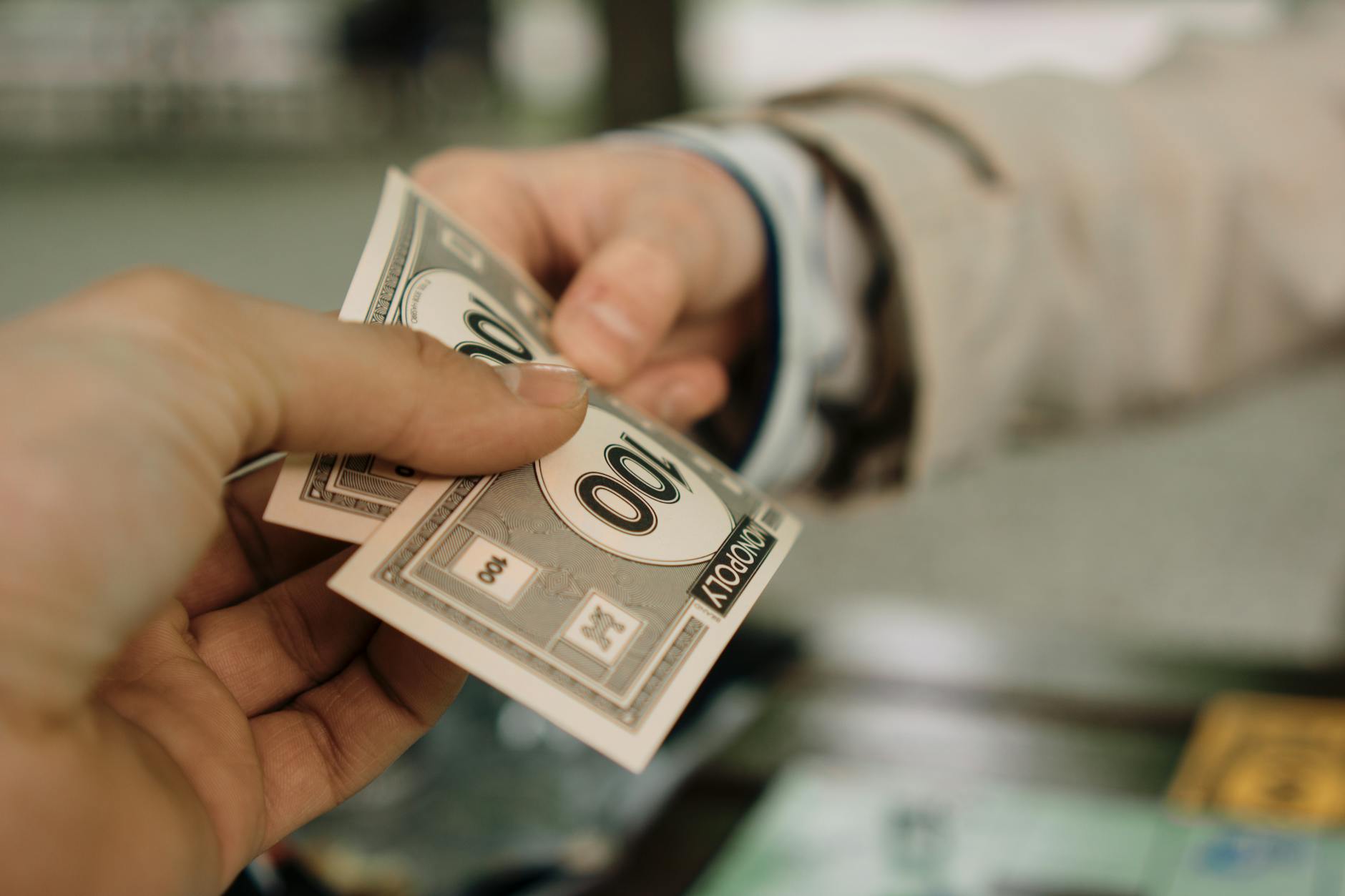 Zbliżenie dłoni wymieniających banknoty Monopoly jako symbol negocjacji