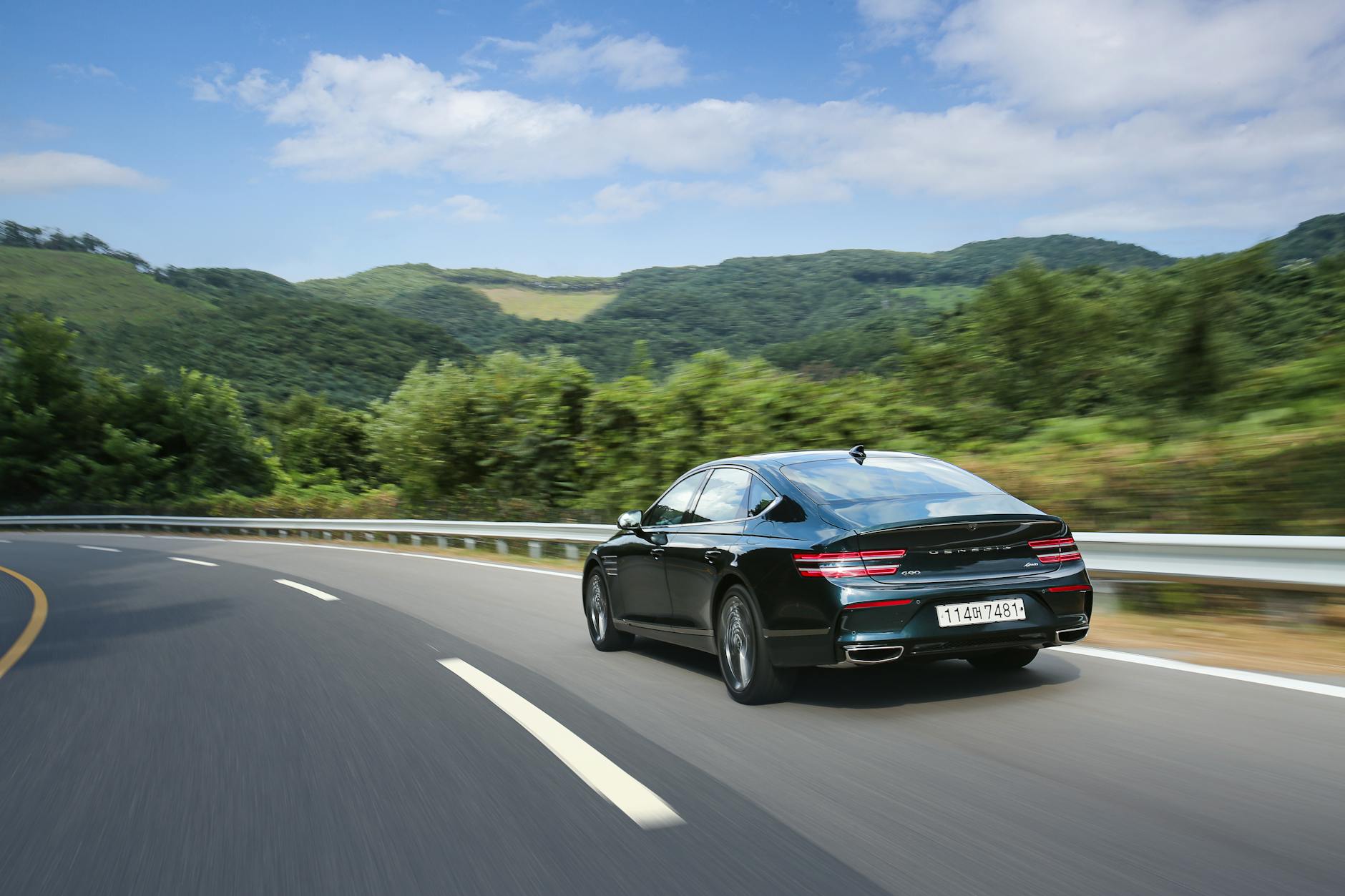 Czarne sportowe auto na krętej górskiej drodze w zielonym krajobrazie