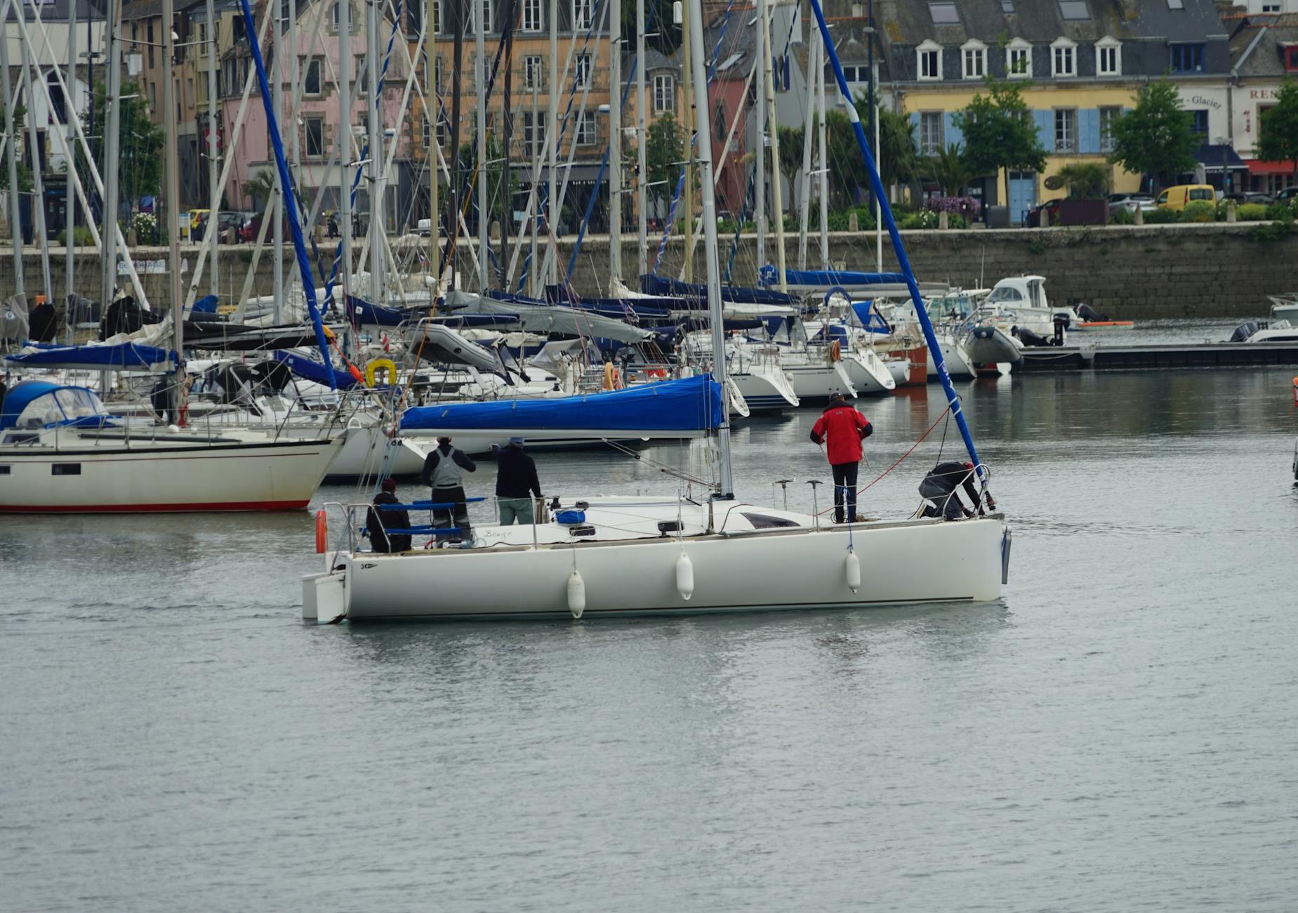 Załoga na jachcie zacumowanym w malowniczej marinie z kolorowymi budynkami