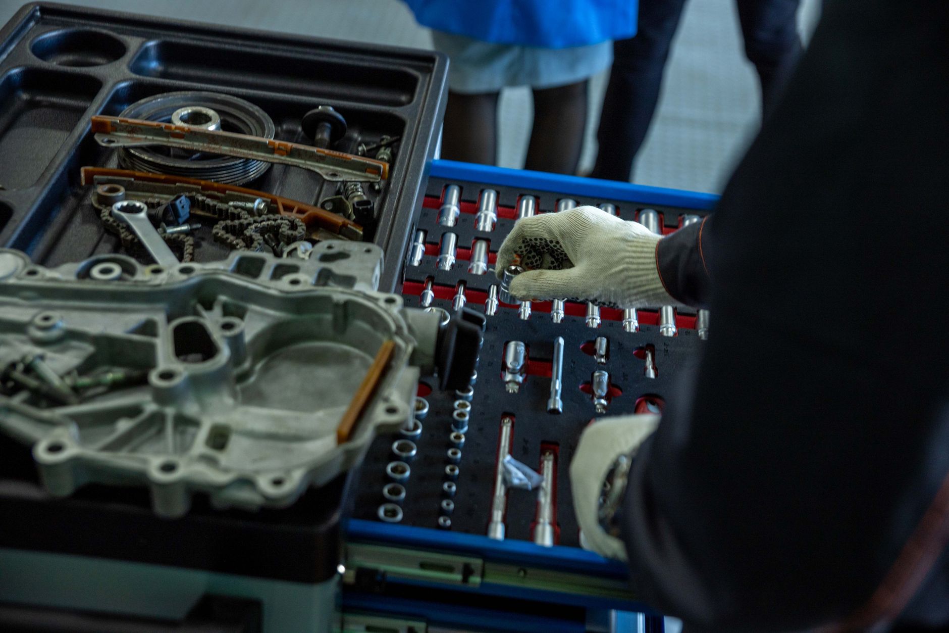 Mechanik w rękawicach sortuje części silnika Jeepa w warsztacie